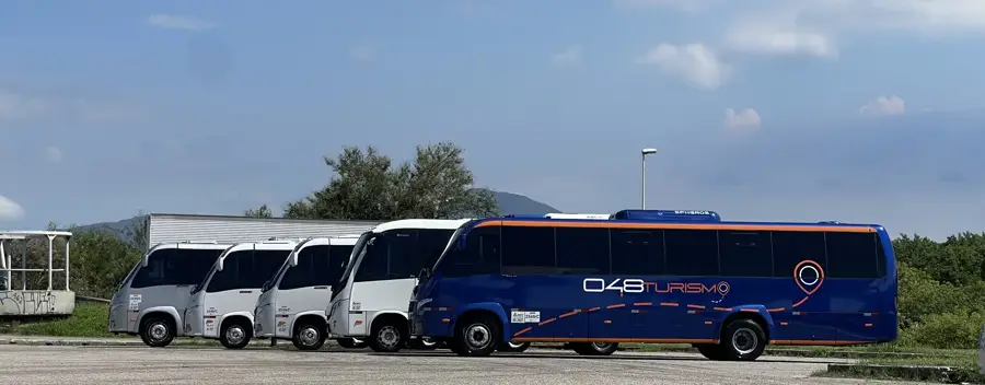 Micro-ônibus e ônibus da frota da 048 Turismo estacionados lado a lado